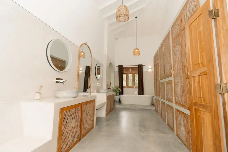 Long bathroom with twin round mirrors and rattan cabinets