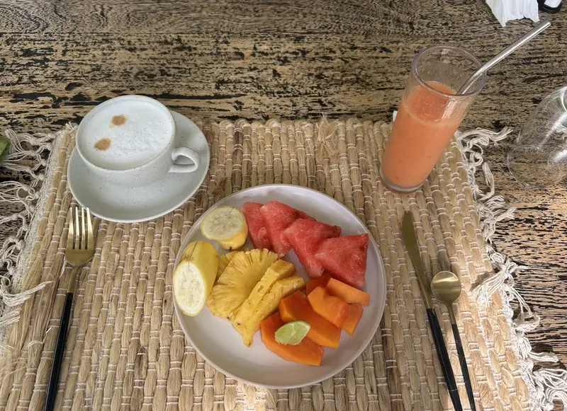 Cappuccino, juice and a plate of tropical fruit