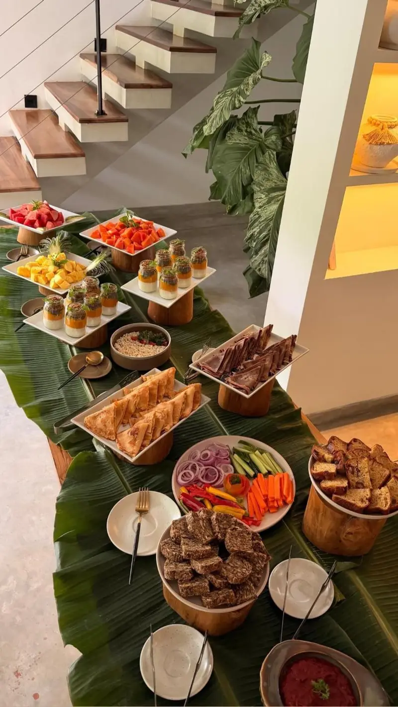 Fresh fruit, dips and bread laid out on banana leaves