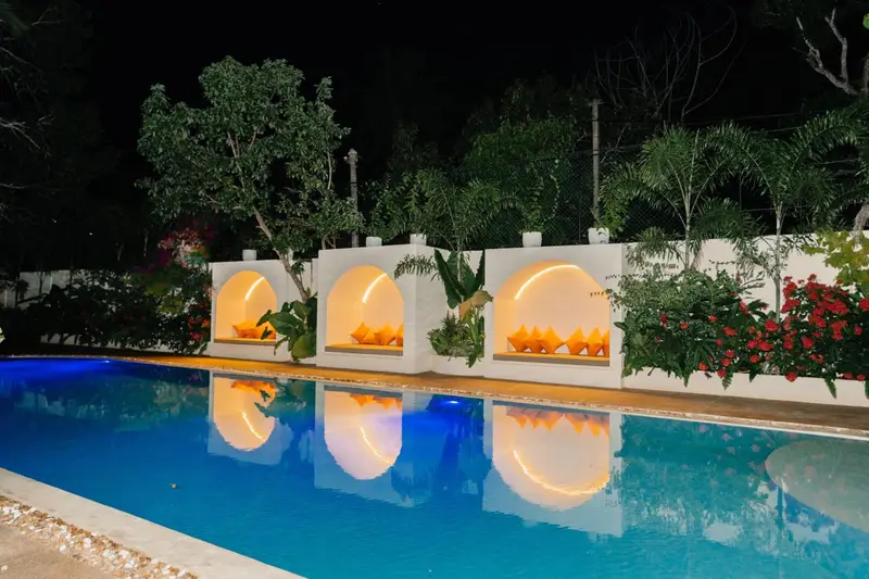 Lit arched cabanas glowing beside the pool at night