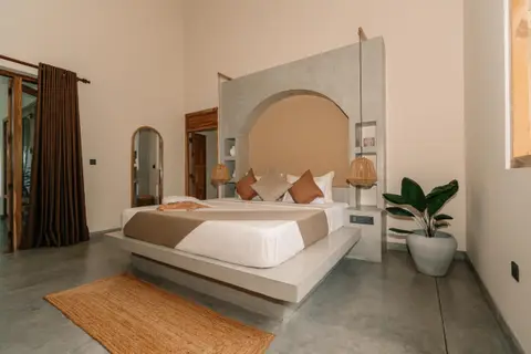 Deluxe Room with arched headboard wall, jute rug and tropical plant