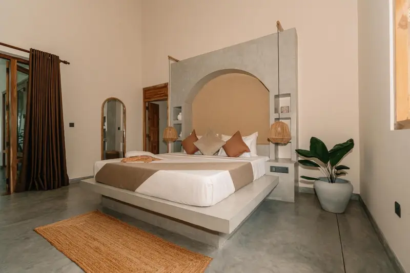 Deluxe Room with arched headboard wall, jute rug and tropical plant