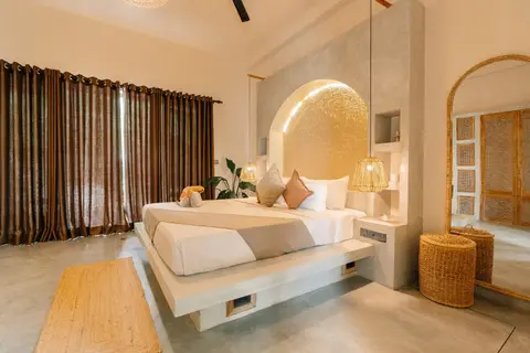 Deluxe Double Room with floating bed, arched gold headboard and rattan mirror