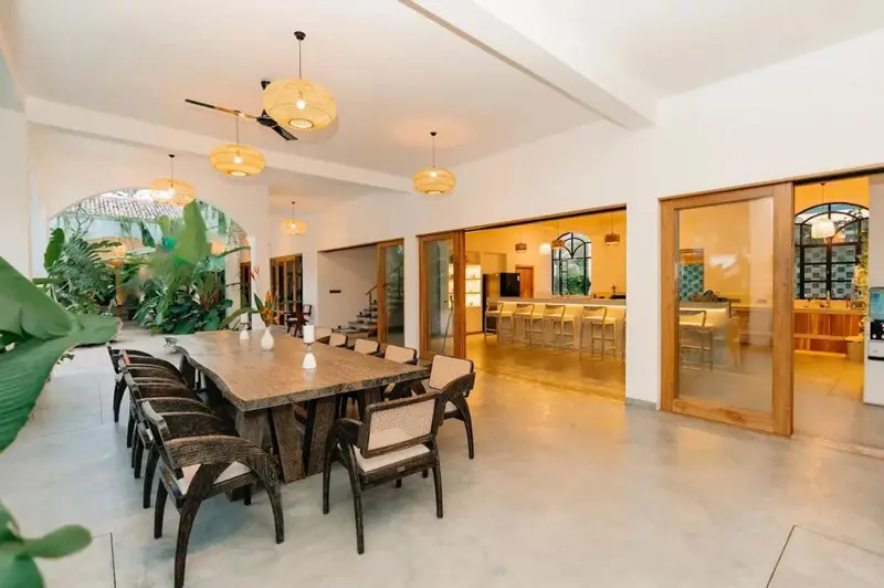 Open dining hall with a long communal table and garden views