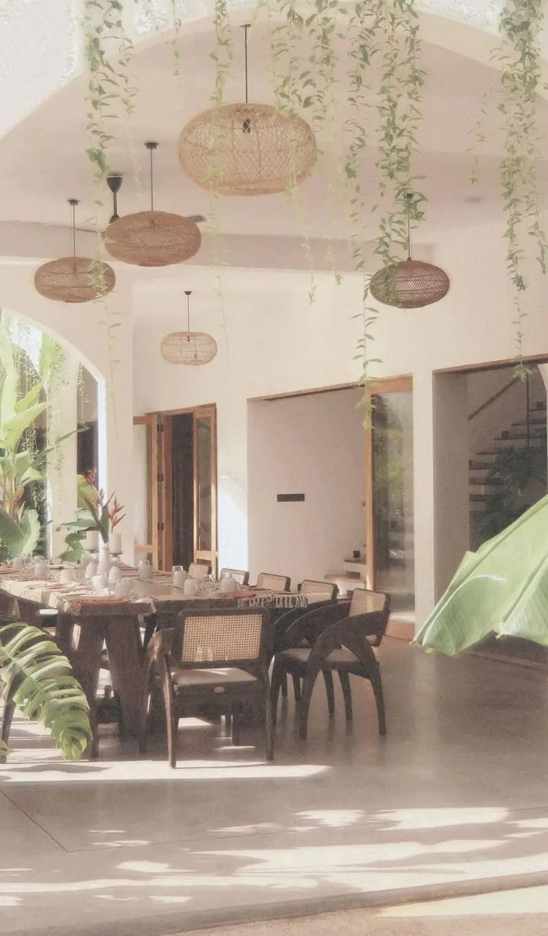 Double-height dining hall with hanging plants and rattan lamps