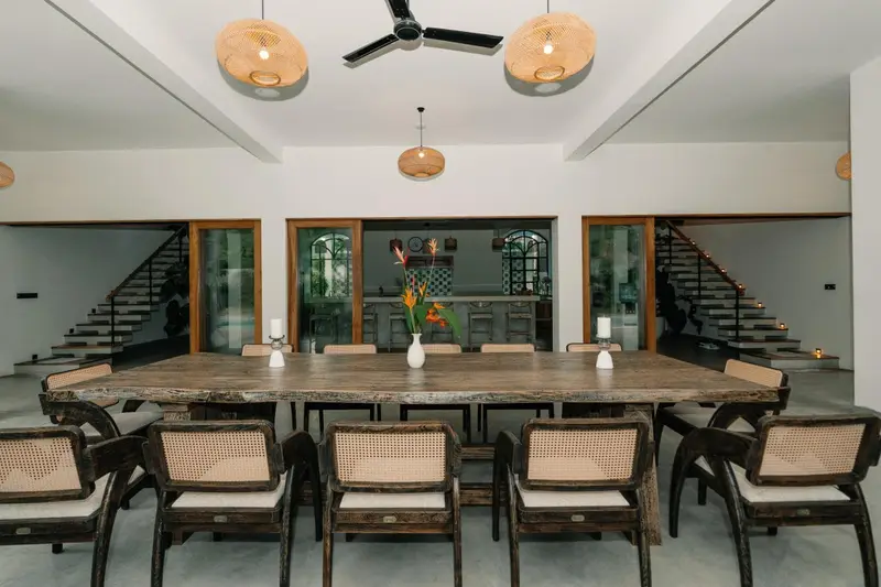 Long live-edge wooden table set beneath rattan lights