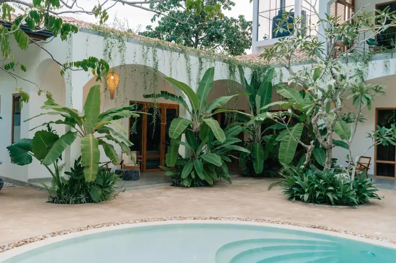 Arched verandas and banana plants around the shallow end of the pool