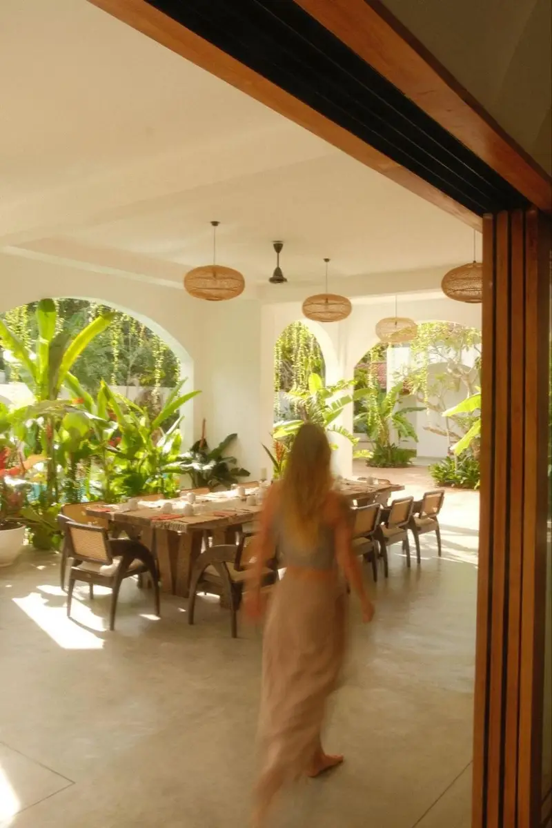 A guest walking through the sunlit dining room