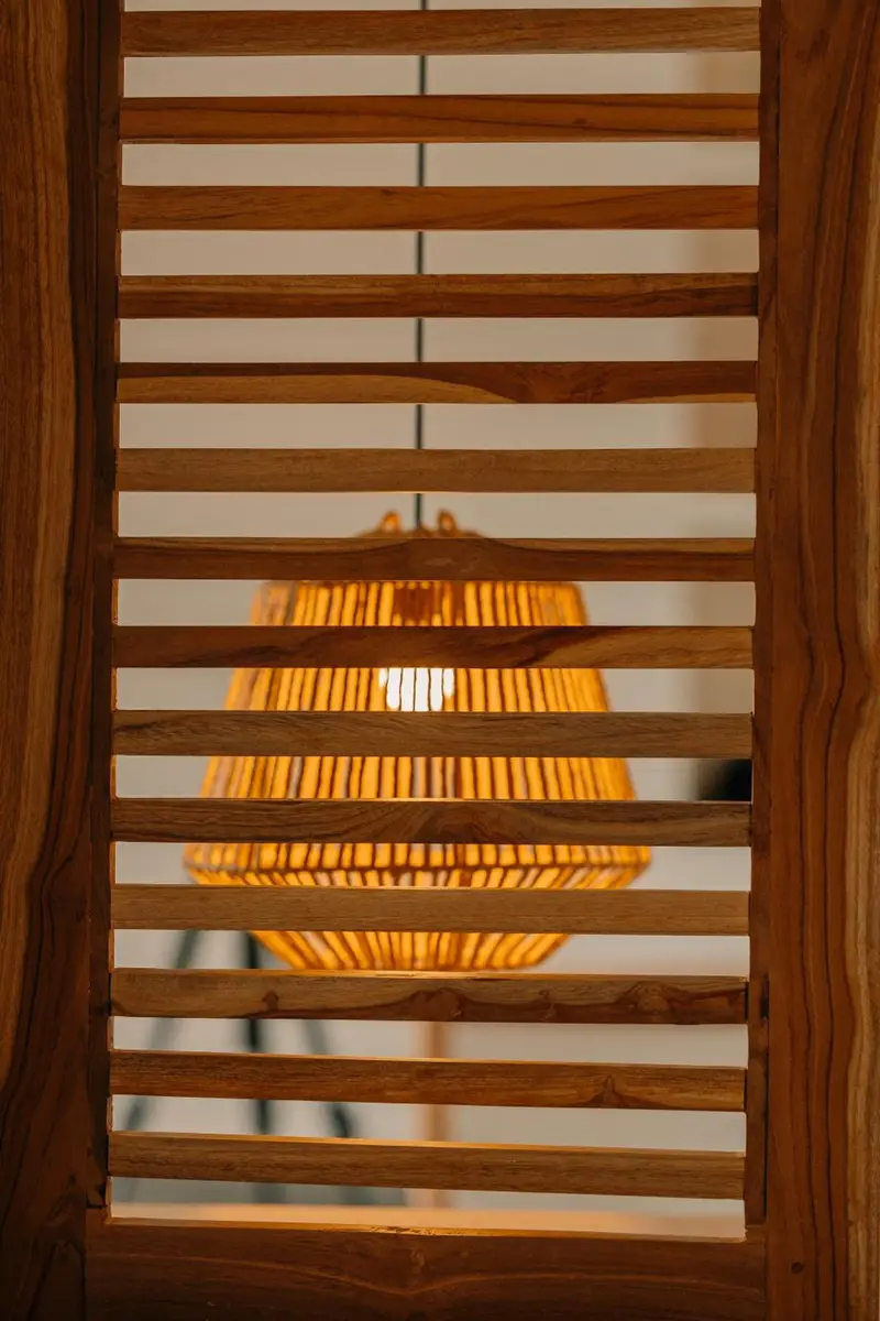 Rattan lamp glowing behind teak louvres