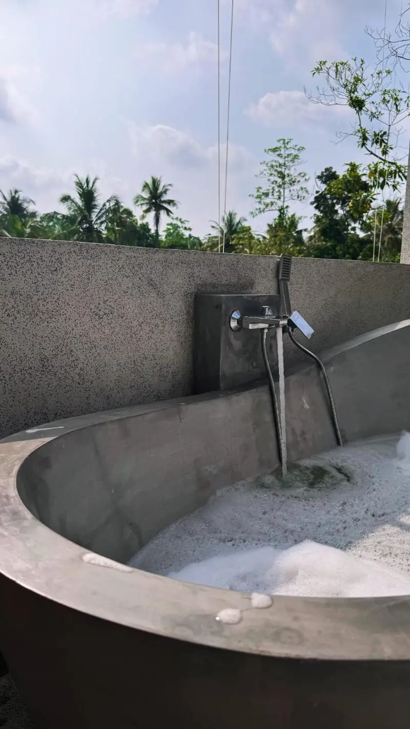 Outdoor concrete bathtub filling under open sky