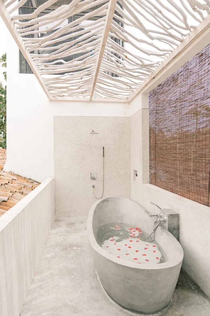 Freestanding outdoor bathtub with petals under a driftwood pergola