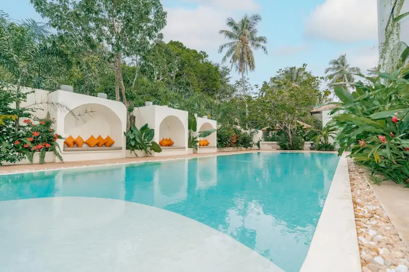 Wide view of the pool, cabanas and coconut palms in the garden