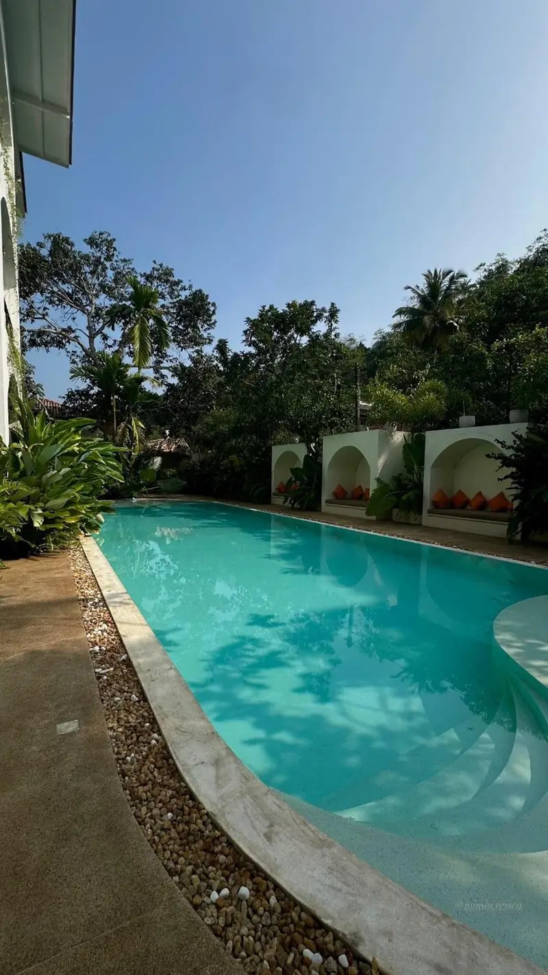 The full length of the pool lined with cabanas and greenery