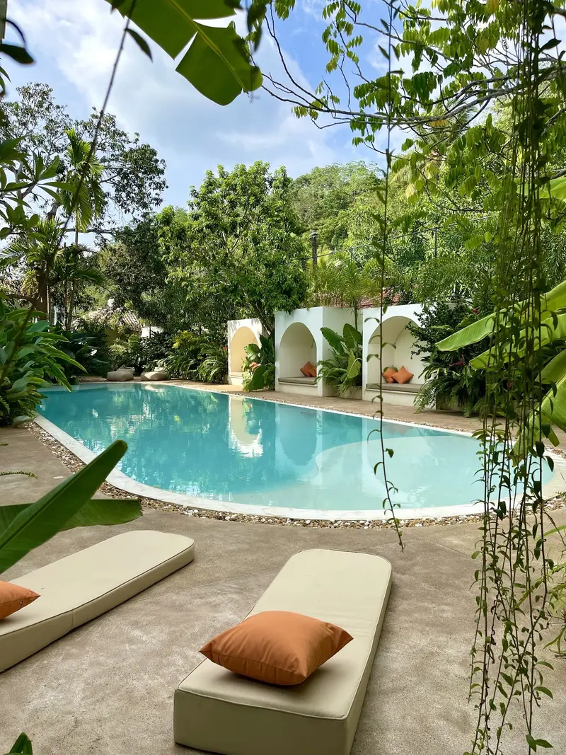 Poolside day beds with orange cushions under the palms