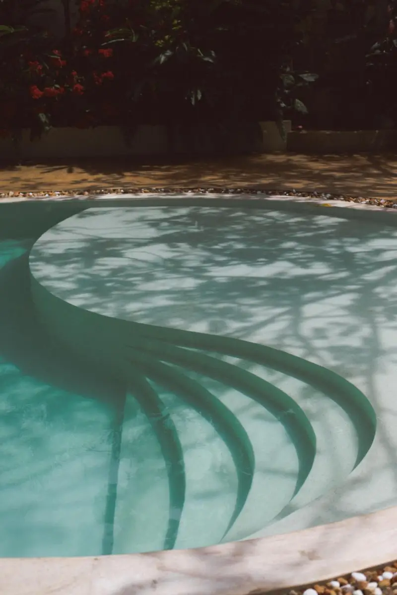 Curved steps leading into the pool under dappled shade
