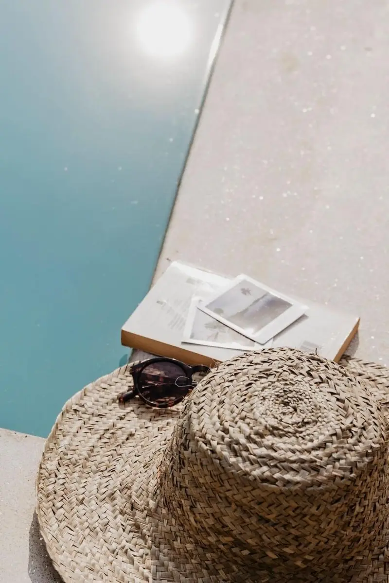Book and woven pouf at the pool's edge