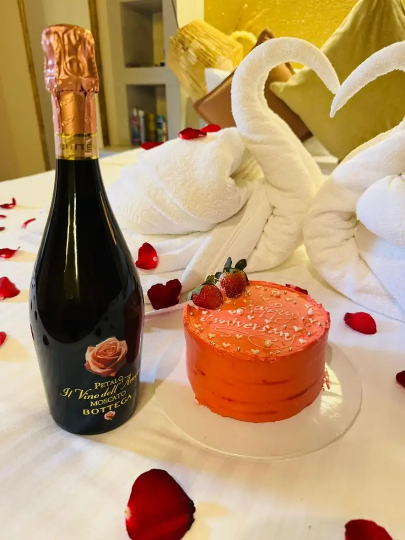 Celebration cake and sparkling wine on a petal-strewn bed