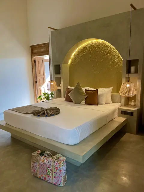 Deluxe Room bed under the glowing arched headboard