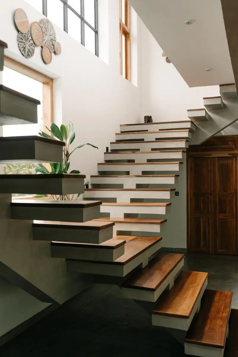 Floating timber stairs beside a double-height window
