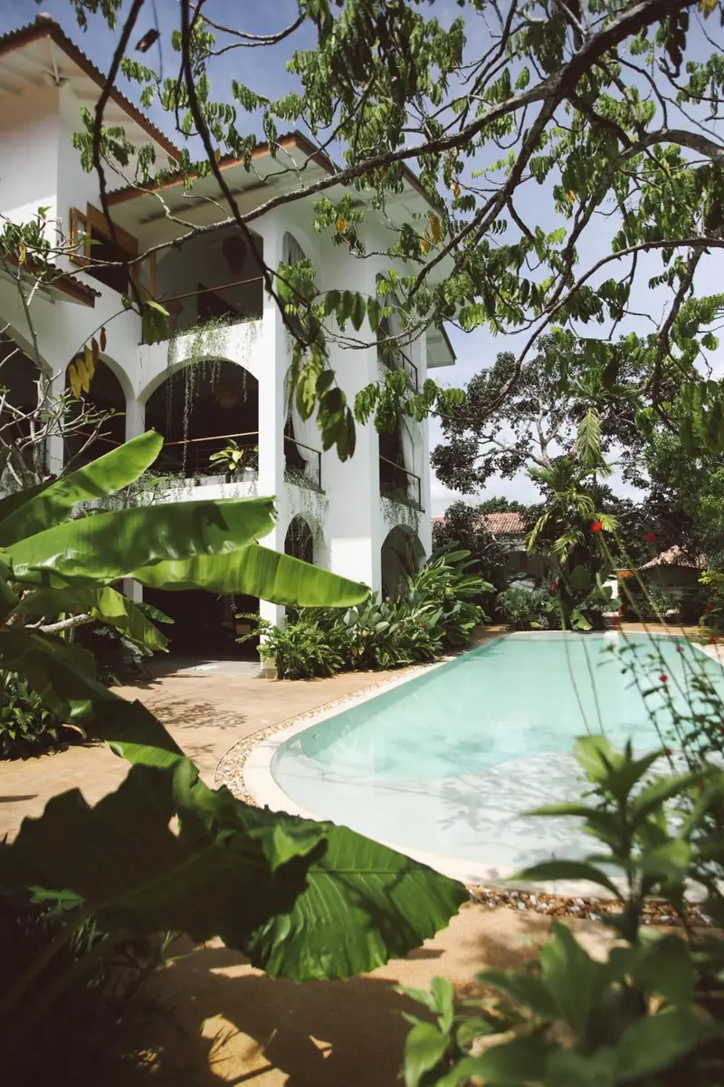 Arched villa seen through the garden canopy above the pool