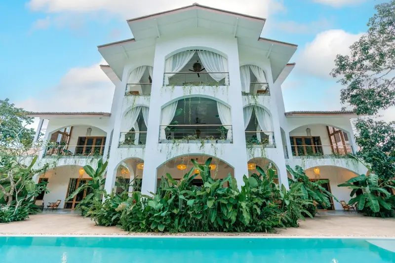 White arched villa at Oura Spirit rising above the pool and tropical garden on a sunny day