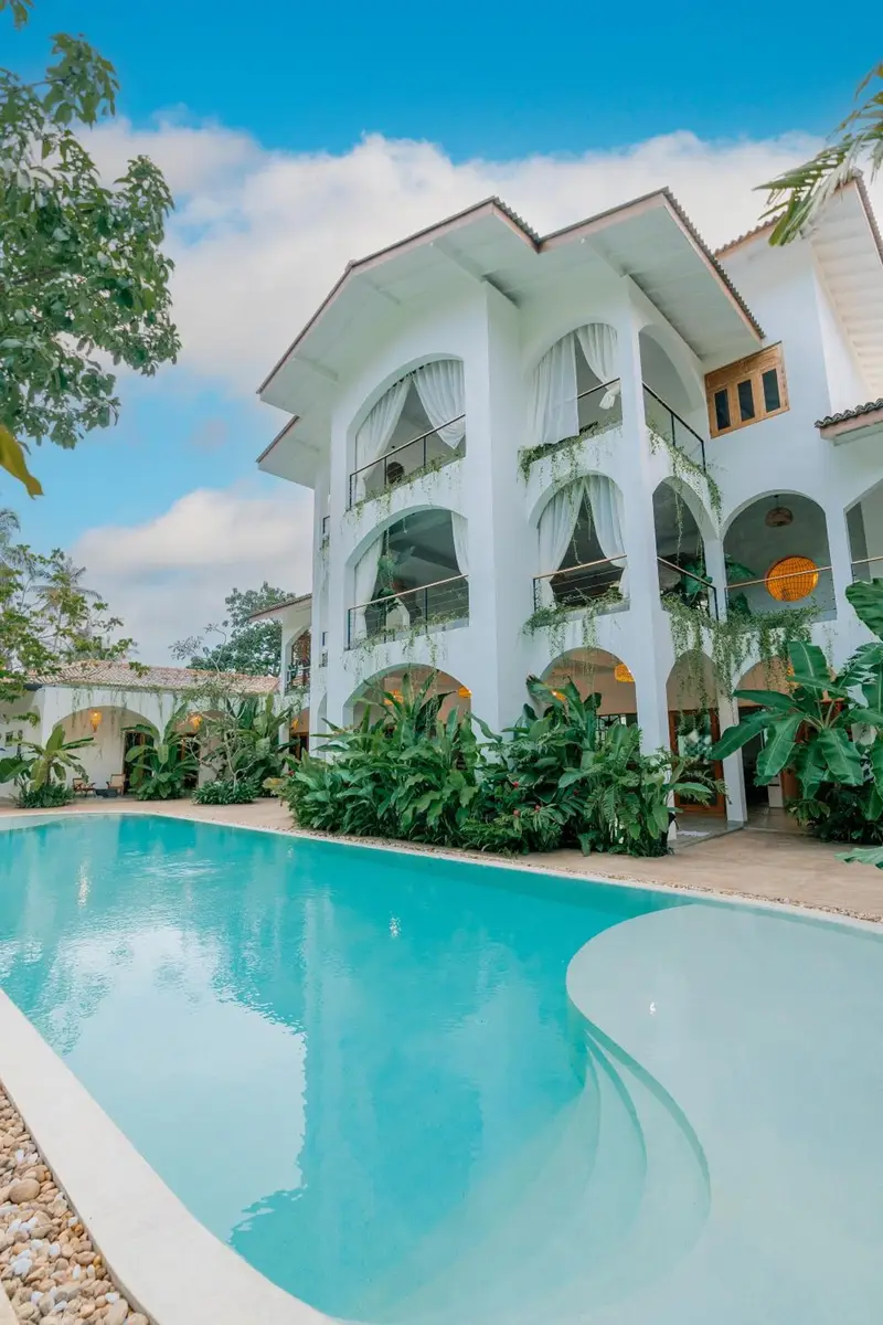The villa's arched facade and the curve of the pool, seen from the garden