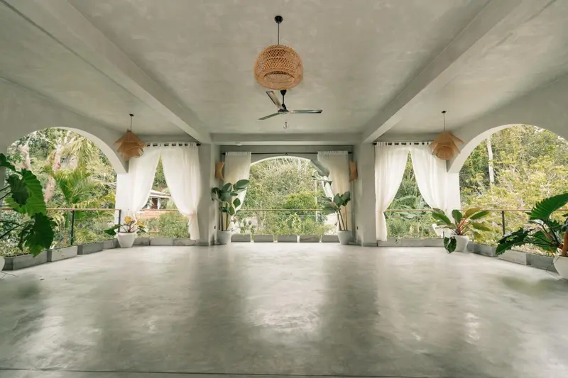 Open-sided yoga hall with arched windows to the jungle